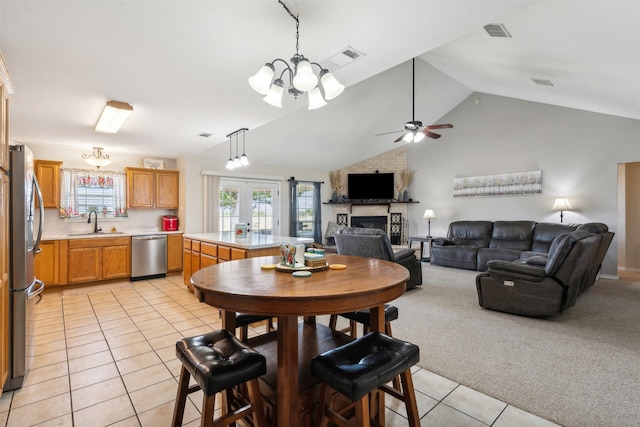 dining room featuring ceiling fan, light carpet, sink, a fireplace, and vaulted ceiling