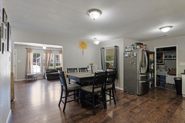 dining area with a textured ceiling and dark hardwood / wood-style floors