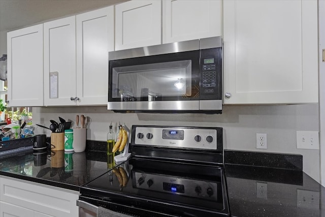 kitchen featuring dark stone countertops, appliances with stainless steel finishes, and white cabinetry