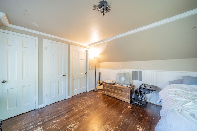 bedroom with dark wood-type flooring, ornamental molding, vaulted ceiling, and two closets