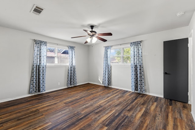 empty room with ceiling fan, plenty of natural light, and dark hardwood / wood-style flooring