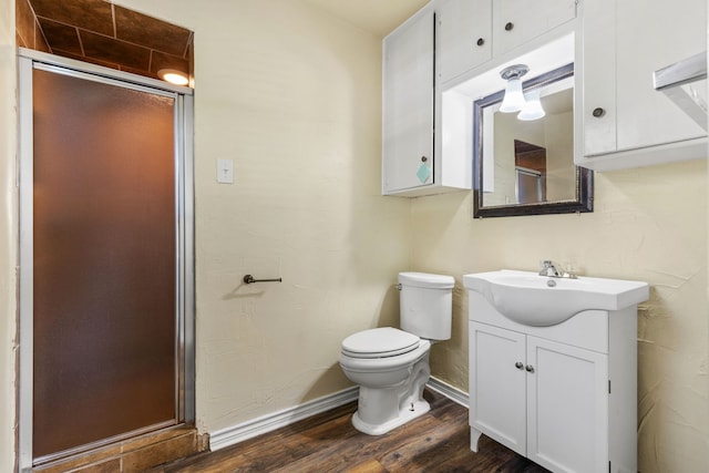 bathroom featuring wood-type flooring, vanity, a shower with shower door, and toilet