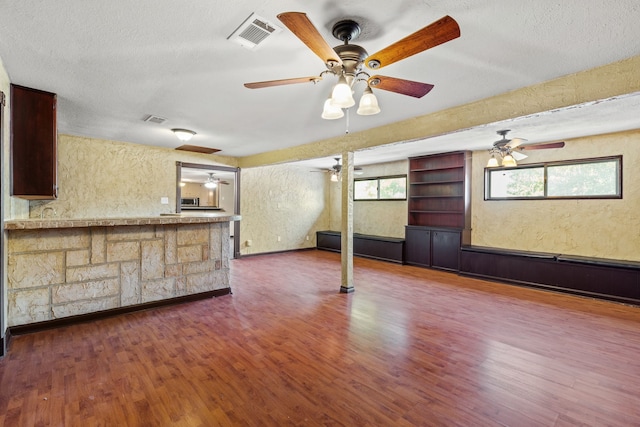 unfurnished living room with dark hardwood / wood-style flooring and a textured ceiling