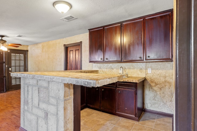 kitchen featuring kitchen peninsula, ceiling fan, light wood-type flooring, and a textured ceiling