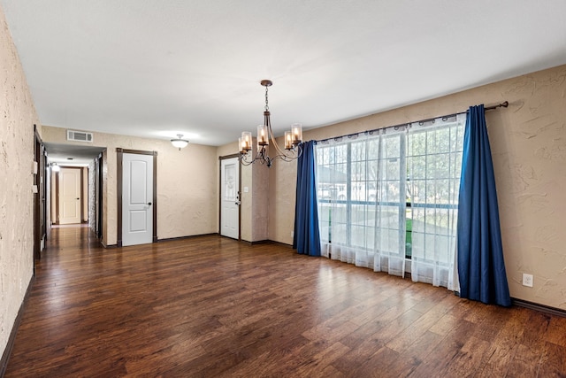 spare room featuring a notable chandelier and dark hardwood / wood-style flooring