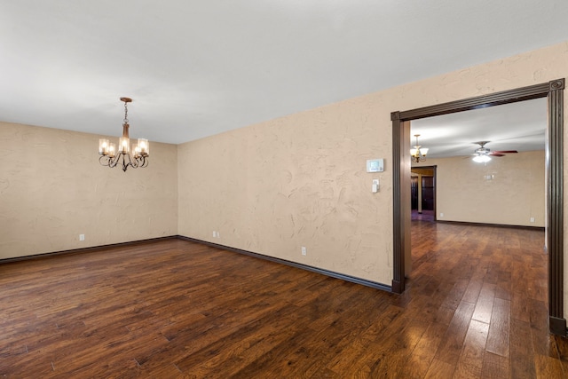 spare room with ceiling fan with notable chandelier and dark hardwood / wood-style floors