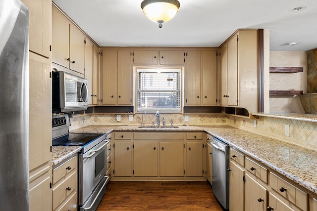 kitchen with dark wood-type flooring, light stone countertops, appliances with stainless steel finishes, and sink