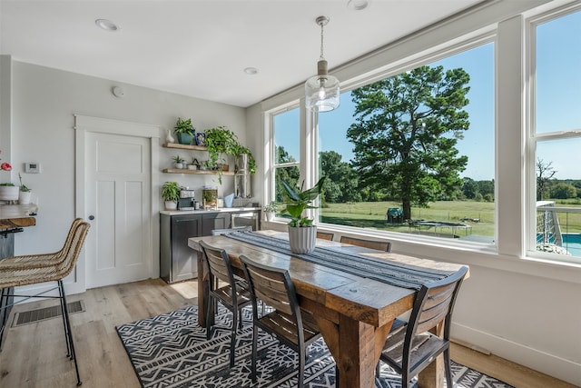 dining area with a wealth of natural light, visible vents, baseboards, and light wood-style floors