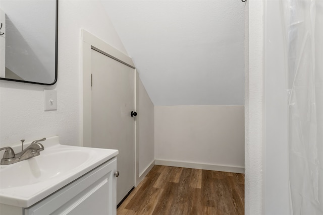 bathroom featuring hardwood / wood-style flooring, lofted ceiling, and vanity