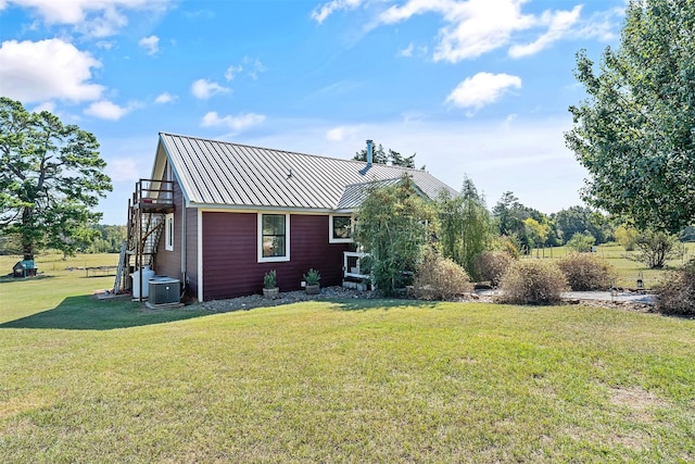 exterior space with a yard, metal roof, cooling unit, and a standing seam roof