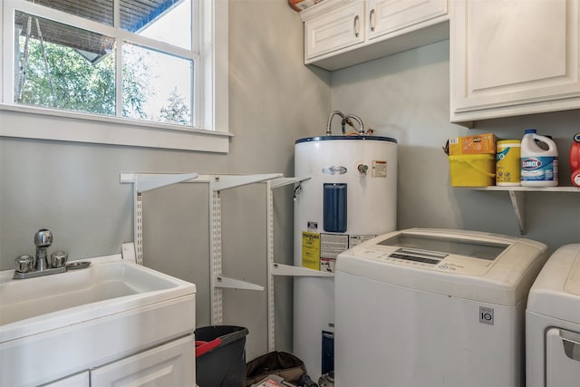 washroom with cabinet space, washing machine and dryer, water heater, and a sink