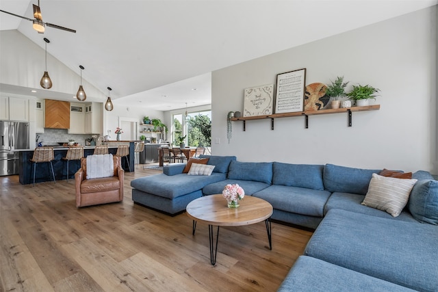 living area with ceiling fan, wood finished floors, and high vaulted ceiling