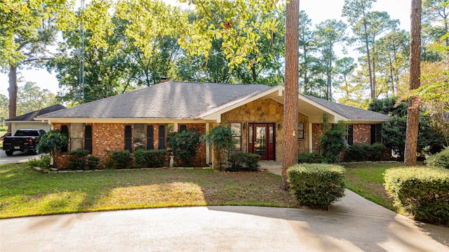 ranch-style home featuring brick siding, a garage, stone siding, and a front yard