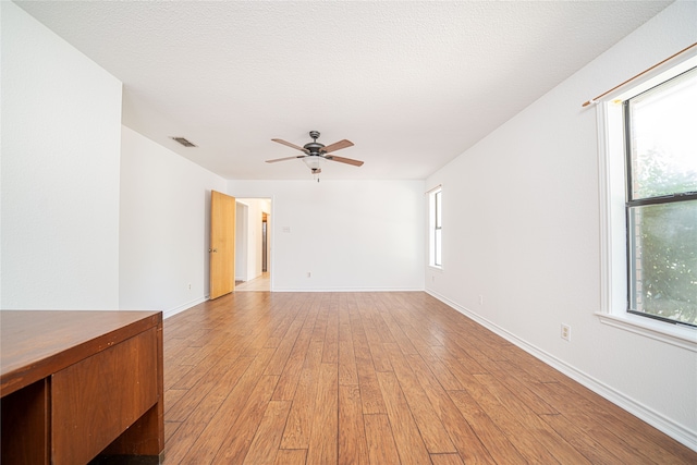 empty room featuring ceiling fan, a textured ceiling, and light hardwood / wood-style floors