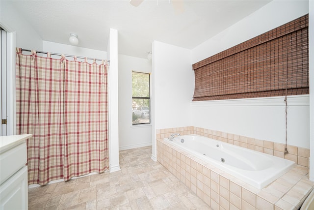 bathroom with stone finish floor, vanity, a tub with jets, baseboards, and a shower with shower curtain