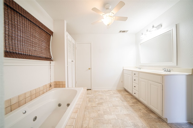 bathroom featuring a textured ceiling, tiled bath, vanity, and ceiling fan