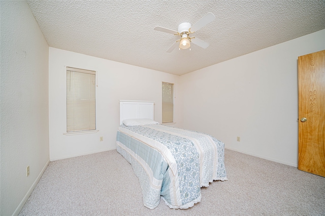 carpeted bedroom featuring ceiling fan and a textured ceiling