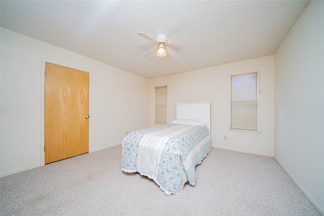 carpeted bedroom with ceiling fan and a textured ceiling