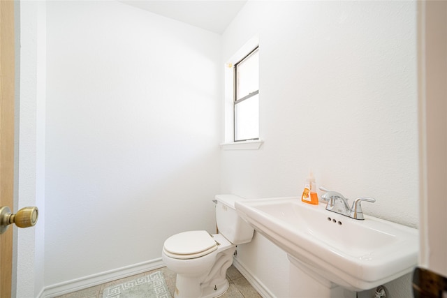 bathroom with a sink, toilet, tile patterned floors, and baseboards