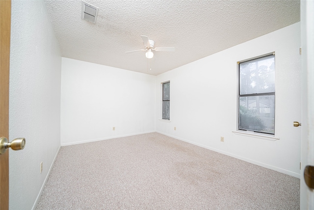 carpeted spare room with ceiling fan and a textured ceiling