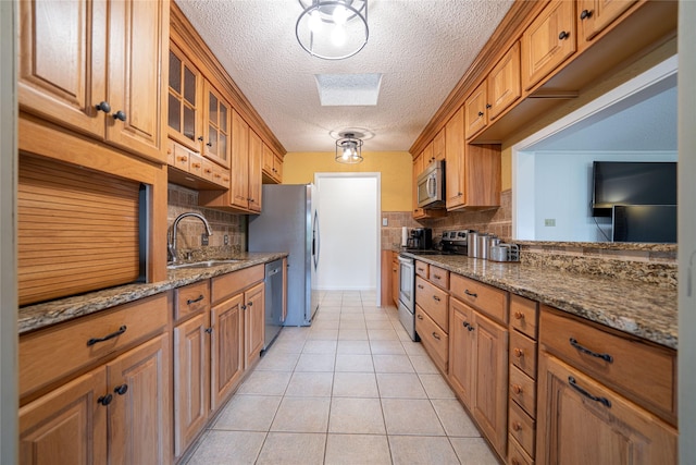 kitchen featuring backsplash, stainless steel appliances, a textured ceiling, and a sink