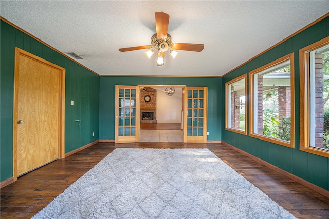 unfurnished room with french doors, a textured ceiling, plenty of natural light, and dark wood-type flooring