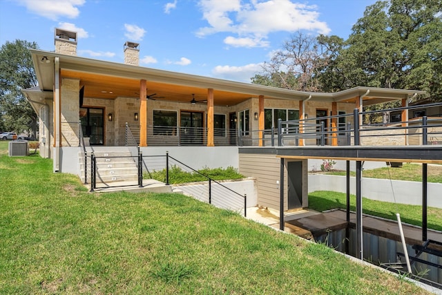 back of house featuring central AC unit and a lawn