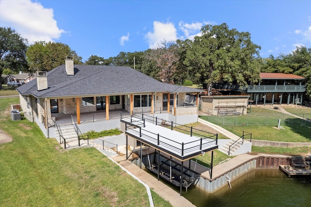 back of house featuring central AC, a yard, and a water view