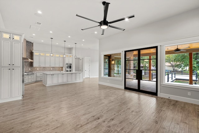 unfurnished living room featuring french doors, ceiling fan, and light hardwood / wood-style flooring