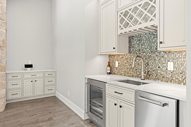 kitchen featuring wine cooler, light stone counters, stainless steel dishwasher, light wood-type flooring, and sink