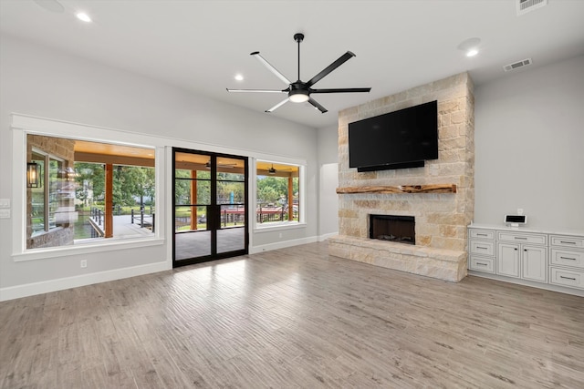 unfurnished living room featuring a stone fireplace, light wood-type flooring, and ceiling fan