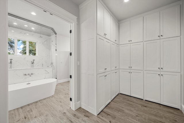 bathroom with wood-type flooring and shower with separate bathtub