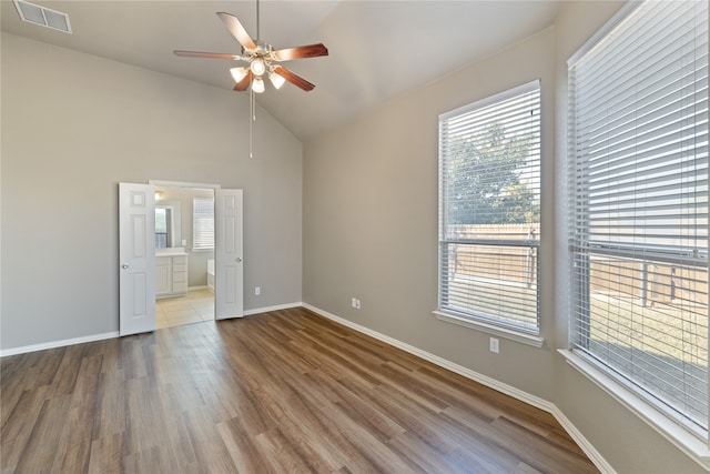 spare room featuring lofted ceiling, plenty of natural light, and hardwood / wood-style floors