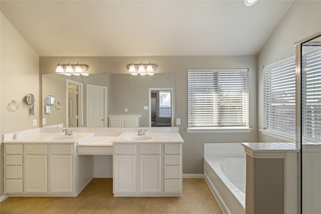 bathroom with tiled tub, vanity, lofted ceiling, and tile patterned floors