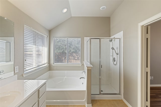 bathroom featuring tile patterned flooring, shower with separate bathtub, vaulted ceiling, and vanity