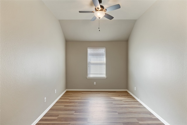 empty room with ceiling fan, light wood-type flooring, and vaulted ceiling