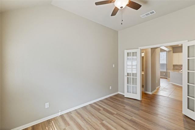 spare room with french doors, light hardwood / wood-style floors, lofted ceiling, and ceiling fan