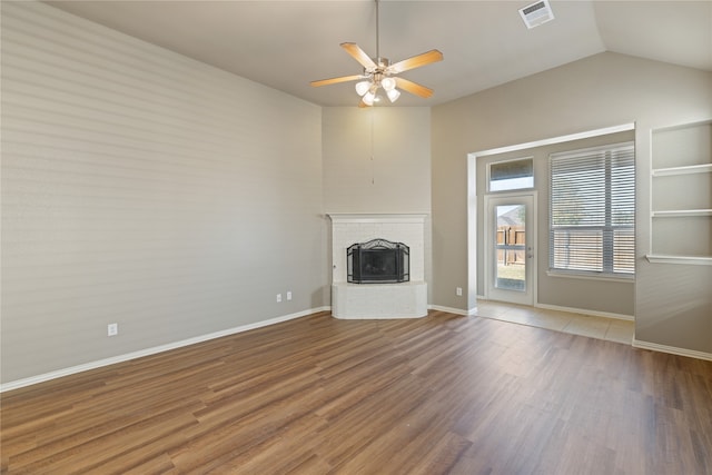 unfurnished living room with wood-type flooring, lofted ceiling, a brick fireplace, and ceiling fan