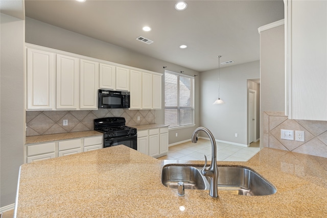 kitchen featuring sink, light stone countertops, backsplash, black appliances, and white cabinetry