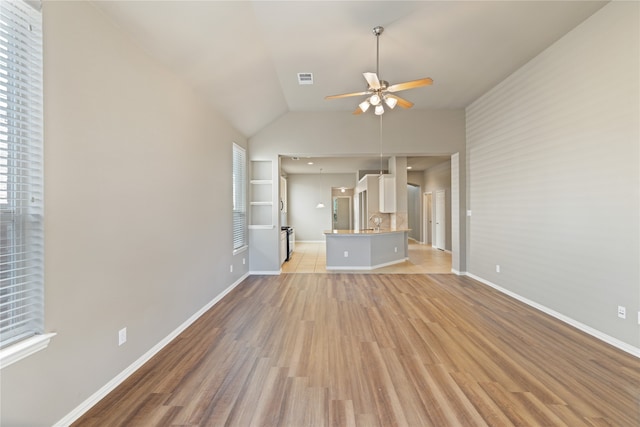 unfurnished living room with lofted ceiling, ceiling fan, sink, and light hardwood / wood-style flooring