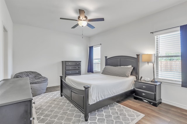 bedroom with ceiling fan, wood-type flooring, and multiple windows