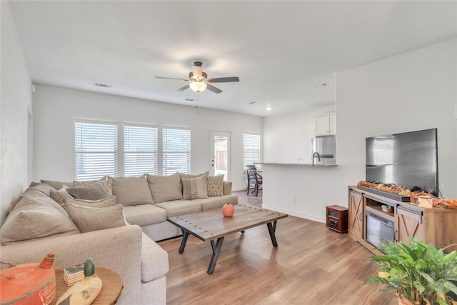 living room with ceiling fan and light wood-type flooring