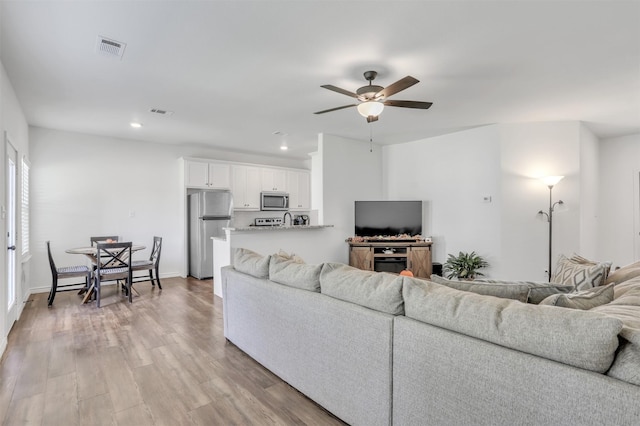 living room featuring light wood-type flooring and ceiling fan