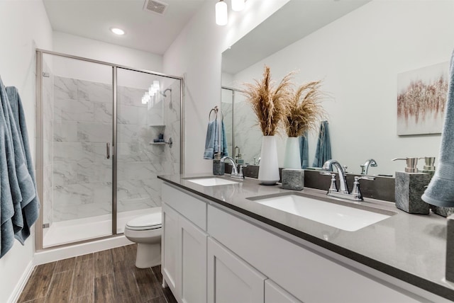 bathroom featuring wood-type flooring, vanity, a shower with shower door, and toilet