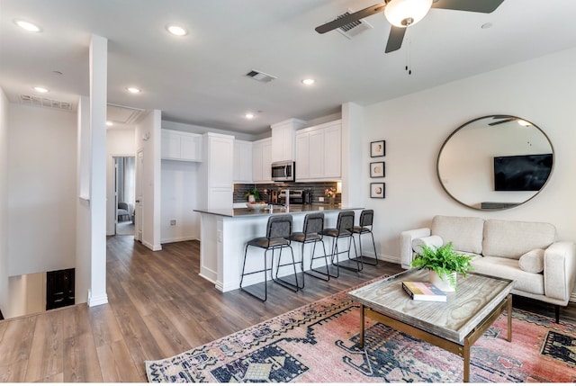 living room featuring ceiling fan and dark hardwood / wood-style flooring