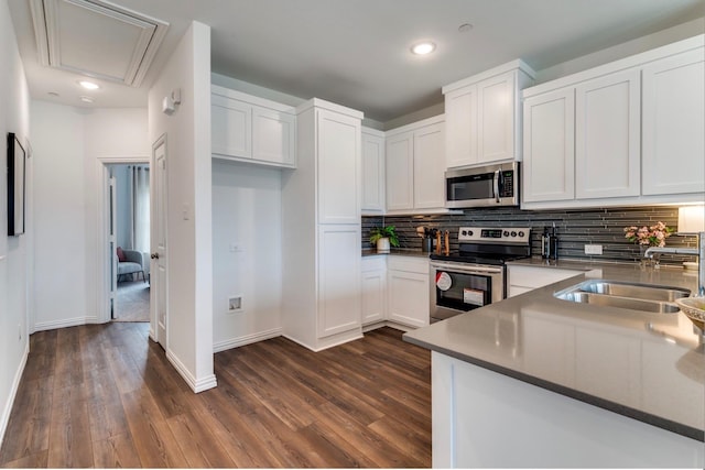 kitchen featuring dark hardwood / wood-style floors, decorative backsplash, white cabinetry, and stainless steel appliances