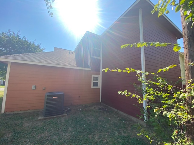 view of side of property with central AC unit and a yard