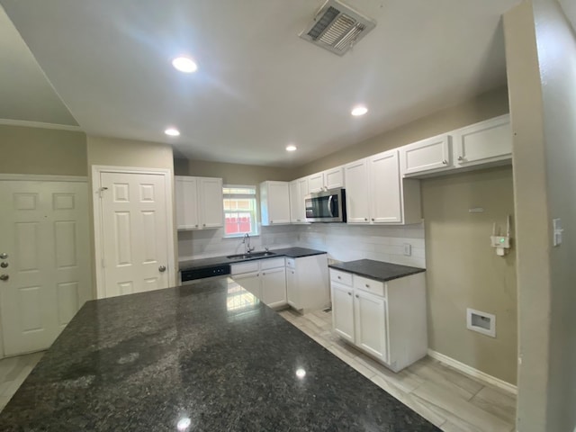 kitchen featuring sink, white cabinetry, appliances with stainless steel finishes, dark stone countertops, and decorative backsplash