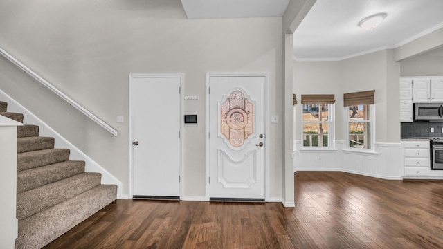 foyer featuring wood finished floors, crown molding, baseboards, and stairs