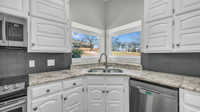 kitchen featuring decorative backsplash, white cabinets, stainless steel appliances, and a sink